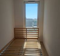 A bright room in a one-bedroom apartment with a bed and a large window.
