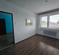 Empty room with laminate flooring in a family house, with a large window and a radiator.
