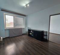 A room in a family house with a window, dark floor, light walls, furniture by the wall.