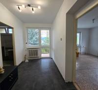 A corridor with tiled flooring leads to the rooms in a family house.