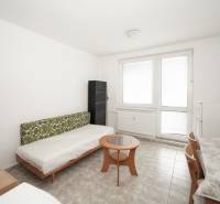 Bright office with a sofa, coffee table, and dining area on a tiled floor.