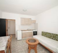 Interior of an office with a kitchenette, table, and sofa.
