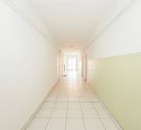 A bright hallway with white walls in an office with tiles and doors.