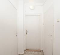 White hallway with closed office doors, a simple space with tiled flooring.