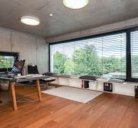 A study in a family house with a large window and wooden floor, modern furniture, view of trees.