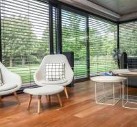 Interior of a family house with comfortable armchairs, wooden flooring, and a view of the garden.