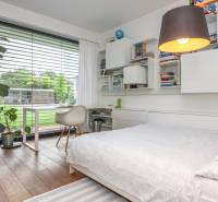 Bedroom in a family house with a bed, shelves, and a large window with a view.