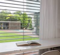 Interior of a family house with a view of the garden and pool through horizontal blinds.