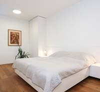 Bedroom in a family house with wooden flooring, a painting, and a nightstand.
