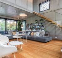 A stylish living room with wooden flooring, a staircase, and large windows in a family house.
