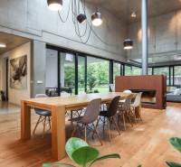 Dining room in a family house with a large wooden table, fireplace, and modern lighting.
