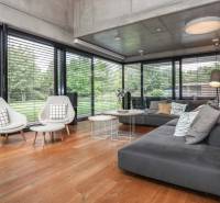 Family house with a glass wall, comfortable furniture, wooden floor, garden view.