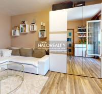 Living room in a 2-room apartment with a white sofa and a mirrored wardrobe.