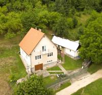 A family house in Papradno surrounded by a grassy plot and trees, access road.