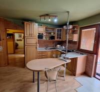 A family house kitchen with wooden furniture, a table, and burgundy walls.