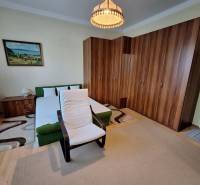 Bedroom in a family house with a bed, an armchair, a large wardrobe, and a painting on the wall.