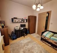 A room in a family house with a desk, a bed, and a wardrobe.