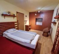 Bedroom of a family house with a bed, wardrobe, and a rattan chair.