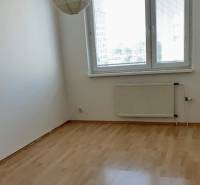 An empty room with a wooden floor, a radiator, and a window in a 3-room apartment.
