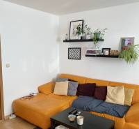 Living room with a yellow sofa and a black table in a 3-room apartment.