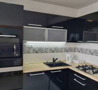 A kitchen in a 3-room apartment with black cabinets, a built-in oven, and a gas stove.