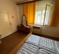 Bedroom in a family house with a window, a mirror, and a bed with a quilted mattress.