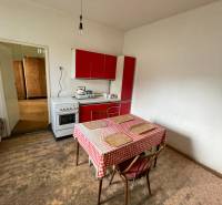 A kitchen in a family house with a dining table and a red kitchen unit.