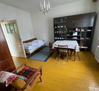Interior of a family house with a dining table, bed, and showcase.