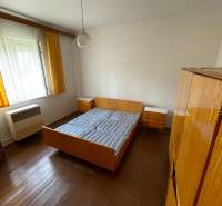 Bedroom in a family house with wooden flooring, bed, and cabinets.