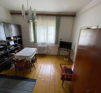 Dining room in a family house with wooden flooring, a simple table, and a cabinet on the wall.