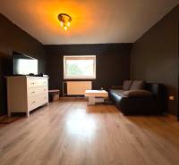 Living room in a 4-room apartment with a black couch and a white sideboard.