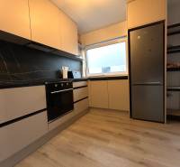 A kitchen in a 4-room apartment with black tiles and built-in appliances.