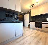 A kitchen with white cabinets in a 4-room apartment, equipped with a dark countertop.