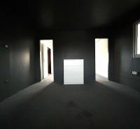 A dark room in a 4-room apartment with a chest of drawers and entrances to other rooms.