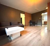 Living room with a gray sofa, white table, and dining area in a 4-room apartment.