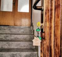 Wooden door with a handle and keys leads to the staircase in a family house.