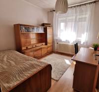 A room in a family house with wooden furniture, a bed, and a rug.