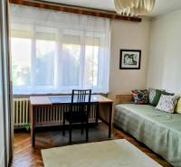 A room in a family house with a desk, bed, carpet, and decorative lighting.