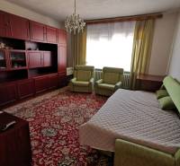 A room in a family house, contains a bed, sofas, a carpet, and a wall cabinet.