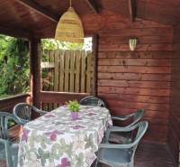 A wooden gazebo in a family house in Topoľčianky, with plastic chairs and a decorated table.
