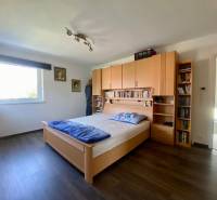Bedroom with a bed, wooden furniture, and a bookshelf in a family house.