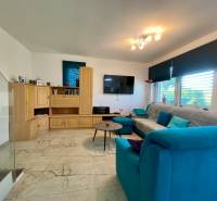 Living room with a light floor, wooden cabinet, and blue sofa in a family house.