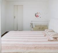 Bright bedroom in a family house with a large bed and a baby crib.