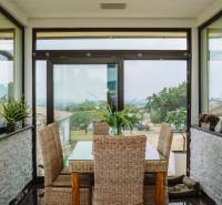Dining room in a family house with rattan furniture and a view of the garden.