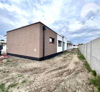 A family house in Miloslavov with a brick facade and a plot next to a concrete fence.