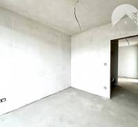 Unfinished room in a family house with white walls and a concrete floor.