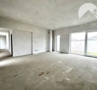 Interior of a family house with large windows and an empty concrete floor.