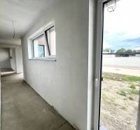 A hallway with windows and an entrance in a family house. The floor is concrete.