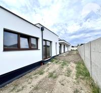 A family house in Miloslavov with a white facade, next to it is a fence and a road.