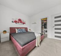 Bedroom with a built-in wardrobe, bed, and decoration with red flowers in a family house.